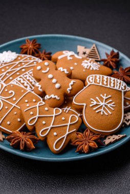 Koyu beton bir masada seramik tabakta farklı renklerde güzel Noel kurabiyeleri.