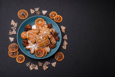 Koyu beton bir masada seramik tabakta farklı renklerde güzel Noel kurabiyeleri.