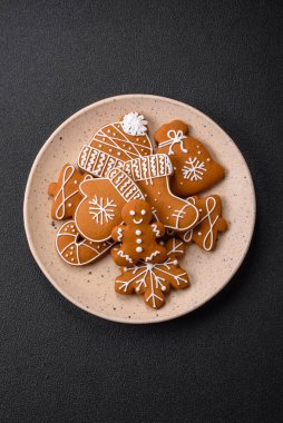 Koyu beton bir masada seramik tabakta farklı renklerde güzel Noel kurabiyeleri.