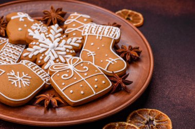 Koyu beton bir masada seramik tabakta farklı renklerde güzel Noel kurabiyeleri.