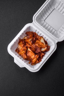 Koyu beton arka planda tuzlu ve baharatlı çıtır patates cipsi.