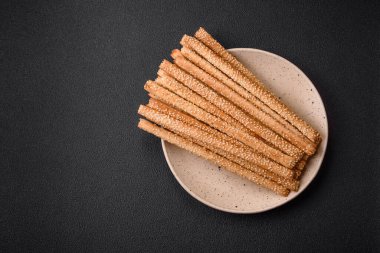 Lezzetli taze Grissini çubukları, koyu beton arka planda tuz ve susam tohumları.