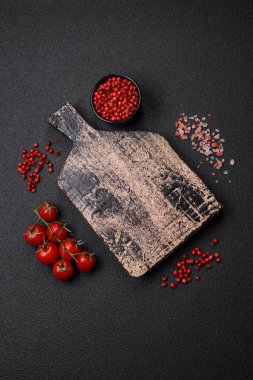 Boş tabak, ahşap kesme tahtası, koyu beton arka planda tuz ve baharatlar.