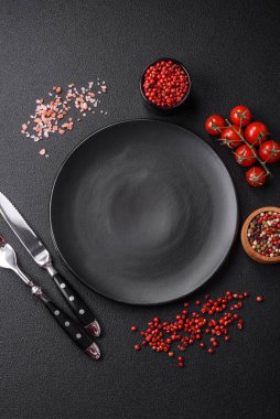 Boş tabak, ahşap kesme tahtası, koyu beton arka planda tuz ve baharatlar.