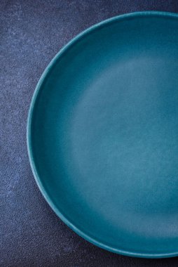 Beton desenli arka planda yuvarlak, boş seramik plaka. Akşam yemeği için tabak ve çatal bıçak hazırlıyorum.