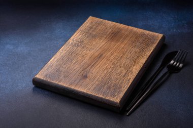 Koyu beton arka planda boş dikdörtgen ahşap kesim tahtası. Evde yemek pişirmek.