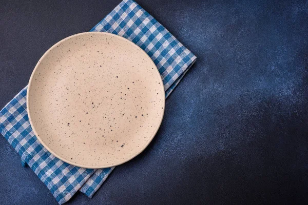 Round empty colored ceramic plate on concrete texture background. Preparing dishes and cutlery for dinner