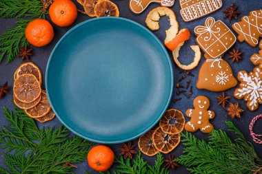 Boş bir tabağın, mandalinanın, zencefilli ekmeğin ve arka planda yıldız anasonunun güzel Noel kompozisyonu.