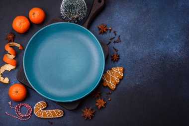 Boş bir tabağın, mandalinanın, zencefilli ekmeğin ve arka planda yıldız anasonunun güzel Noel kompozisyonu.