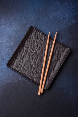 Beton desenli arka planda yuvarlak, boş seramik plaka. Akşam yemeği için tabak ve çatal bıçak hazırlıyorum.