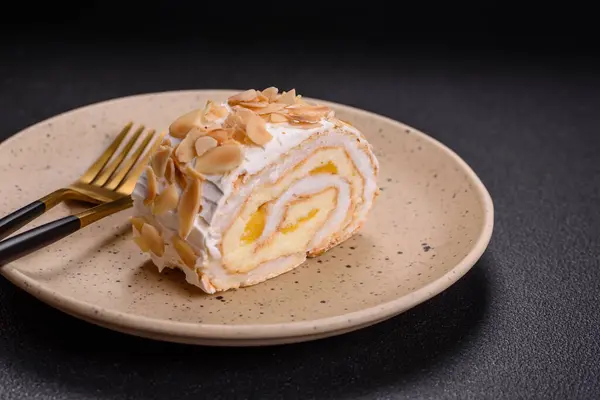 A piece of delicious sweet meringue roll with mascarpone cheese, berries and almonds on a dark concrete background