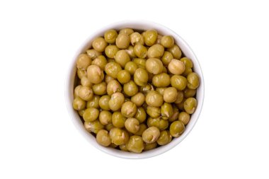 Lezzetli konserve yeşil bezelyeler beyaz bir kasede tuz ve baharatlarla koyu beton bir zemin üzerinde