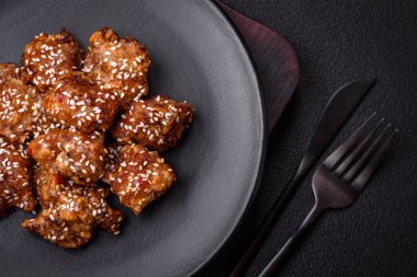 Lezzetli Asya yemeği teriyaki soslu tavuk parçaları ve koyu beton arka planda tuz ve baharatlar.