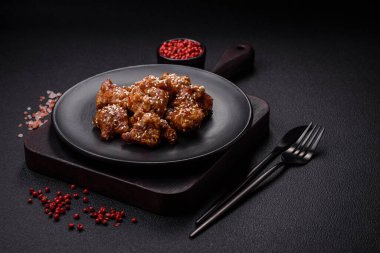 Lezzetli Asya yemeği teriyaki soslu tavuk parçaları ve koyu beton arka planda tuz ve baharatlar.