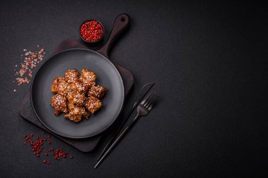 Lezzetli Asya yemeği teriyaki soslu tavuk parçaları ve koyu beton arka planda tuz ve baharatlar.