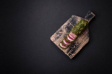 Lezzetli taze pastırma şeritleri, baharatlar ve koyu beton arka planda tuz.