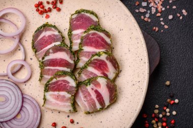 Lezzetli taze pastırma şeritleri, baharatlar ve koyu beton arka planda tuz.