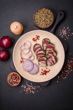 Lezzetli taze pastırma şeritleri, baharatlar ve koyu beton arka planda tuz.