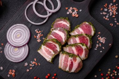 Lezzetli taze pastırma şeritleri, baharatlar ve koyu beton arka planda tuz.