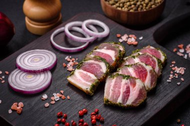 Lezzetli taze pastırma şeritleri, baharatlar ve koyu beton arka planda tuz.