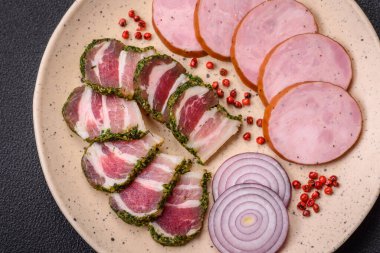 Tuzlu ve baharatlı lezzetli füme sosis koyu beton arka planda dilimler halinde kesilmiş.