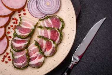 Lezzetli taze pastırma şeritleri, baharatlar ve koyu beton arka planda tuz.