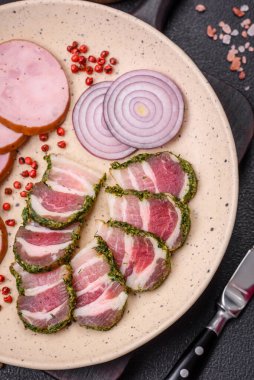 Lezzetli taze pastırma şeritleri, baharatlar ve koyu beton arka planda tuz.