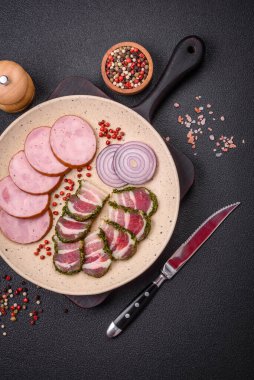 Tuzlu ve baharatlı lezzetli füme sosis koyu beton arka planda dilimler halinde kesilmiş.