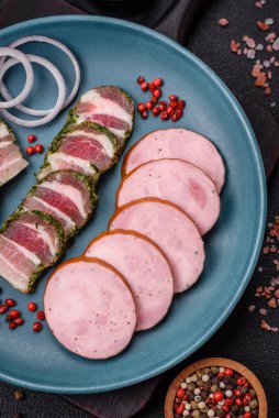 Tuzlu ve baharatlı lezzetli füme sosis koyu beton arka planda dilimler halinde kesilmiş.