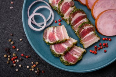 Lezzetli taze pastırma şeritleri, baharatlar ve koyu beton arka planda tuz.