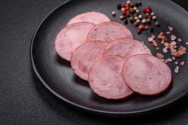 Tuzlu ve baharatlı lezzetli füme sosis koyu beton arka planda dilimler halinde kesilmiş.