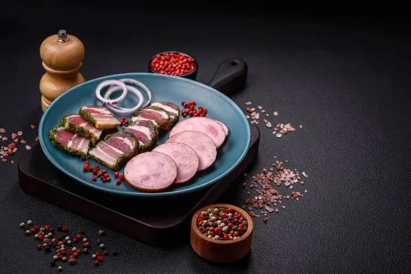 Tuzlu ve baharatlı lezzetli füme sosis koyu beton arka planda dilimler halinde kesilmiş.