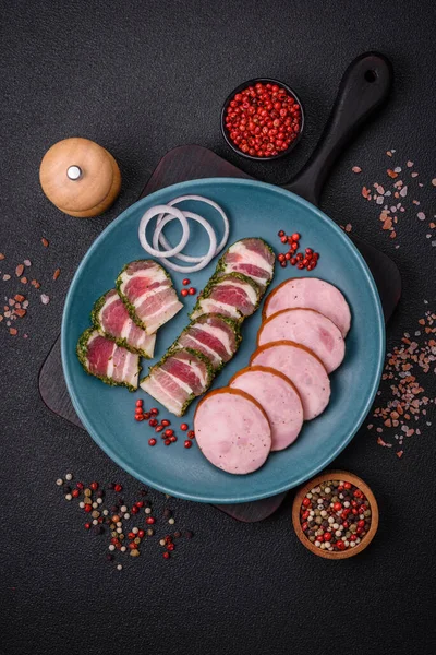 Tuzlu ve baharatlı lezzetli füme sosis koyu beton arka planda dilimler halinde kesilmiş.