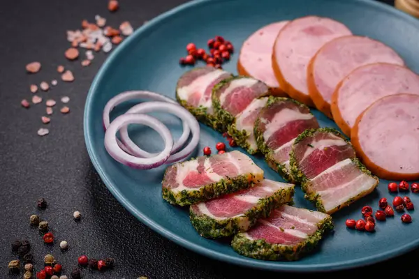 Tuzlu ve baharatlı lezzetli füme sosis koyu beton arka planda dilimler halinde kesilmiş.