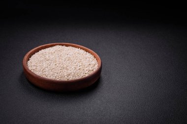 Yuvarlak bir seramik kasede, koyu beton arka planda pişmemiş beyaz pirinç. Asya yemeği pişirmek