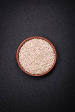 Yuvarlak bir seramik kasede, koyu beton arka planda pişmemiş beyaz pirinç. Asya yemeği pişirmek