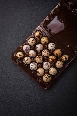 Koyu beton arka planda plastik bir kutuda çiğ bıldırcın yumurtası. Besleyici bir kahvaltı hazırlıyorum.