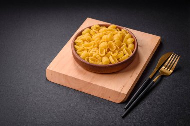 Ham durum buğday gnocchi makarna ile tuz ve baharatlar seramik bir tabakta koyu beton zemin üzerinde