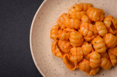 Pesto soslu lezzetli taze makarna, tuz, baharatlar ve çimento kaplı seramik bir tabakta otlar.