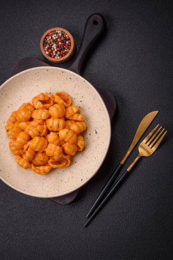 Pesto soslu lezzetli taze makarna, tuz, baharatlar ve çimento kaplı seramik bir tabakta otlar.