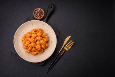 Pesto soslu lezzetli taze makarna, tuz, baharatlar ve çimento kaplı seramik bir tabakta otlar.