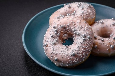 Gümüş boncuklu ve koyu beton arka planda kremalı lezzetli, taze, beyaz ya da bej bir çörek.