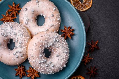 Gümüş boncuklu ve koyu beton arka planda kremalı lezzetli, taze, beyaz ya da bej bir çörek.