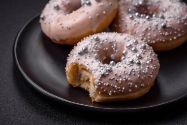 Gümüş boncuklu ve koyu beton arka planda kremalı lezzetli, taze, beyaz ya da bej bir çörek.