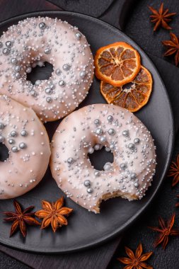 Gümüş boncuklu ve koyu beton arka planda kremalı lezzetli, taze, beyaz ya da bej bir çörek.