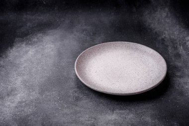 Boş yuvarlak seramik tabağı desenli beton arka planda mutfak gereçleri olarak kullan