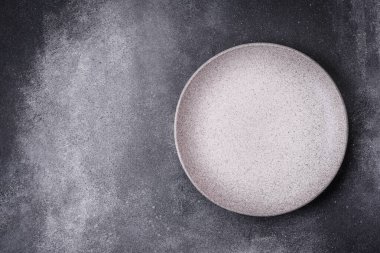 Boş yuvarlak seramik tabağı desenli beton arka planda mutfak gereçleri olarak kullan