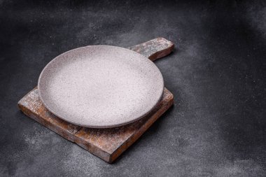 Boş yuvarlak seramik tabağı desenli beton arka planda mutfak gereçleri olarak kullan