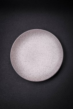 Boş yuvarlak seramik tabağı desenli beton arka planda mutfak gereçleri olarak kullan