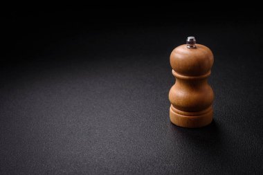 Güzel ahşap şekilli biber ya da koyu dokulu arka planda değirmeni olan tuzluk.